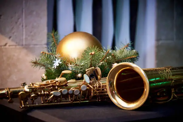 Photo of Christmas decoration and golden saxophone on wall background.