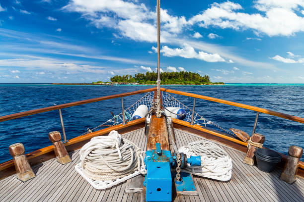 luxury sailing boat yacht in front of tropical paradise maldives island resort with coral reef and blue ocean water tourism background - yacht luxury front view ships bow imagens e fotografias de stock