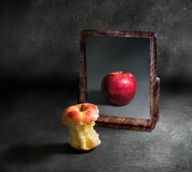 Photo of apple with anorexia looking at its reflection in a mirror