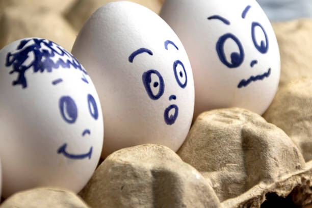 istock Lovely eggs in cardboard box. Eggs with emotions. White eggs in cardboard box with different faces painted on them. Boys and girl 1170325881