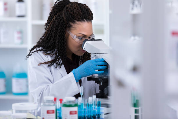 istock Scientist looks intently into microscope to view experiment results 1170328861