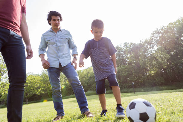 istock Father and uncle help young boy learn to play soccer 1170329416