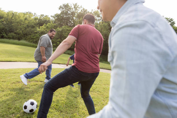 istock Multi-generational group of men kick soccer ball around 1170329437