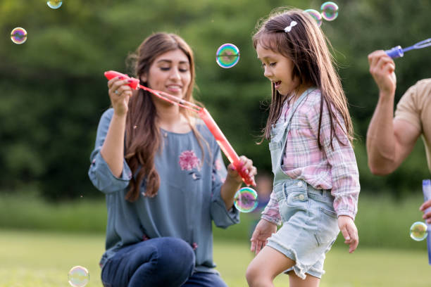 istock Young family of three plays with bubbles at park 1170329485
