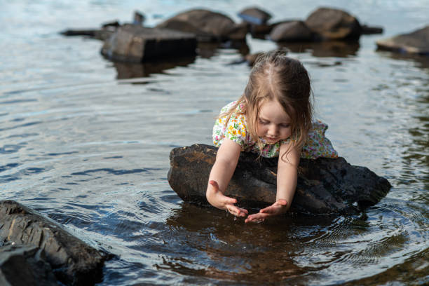 Two year old girl playing in a lake on a Summer afternoon.