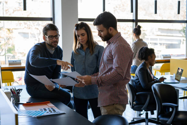 istock Group of creatives working on a project looking at some documents very focused in a coworking office 1170332142