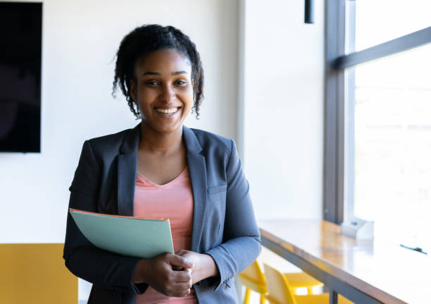 istock Black beautiful confident businesswoman at the office holding some folders while facing camera smiling 1170332225
