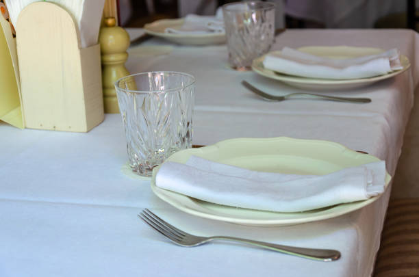 Table setting. Restaurant interior. Clean plates, glasses and cutlery on a white tablecloth. Preparing for guest service. Closeup