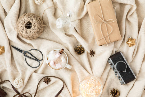 Winter cozy background with cup of coffee and marshmallow, warm blanket and gifts. Flat lay