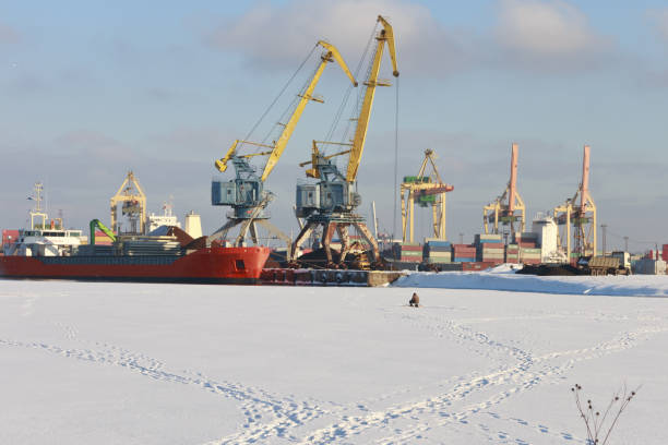 Beautiful multi-colored cranes in a small port. Low-ice fisherman in the river bay in winter.