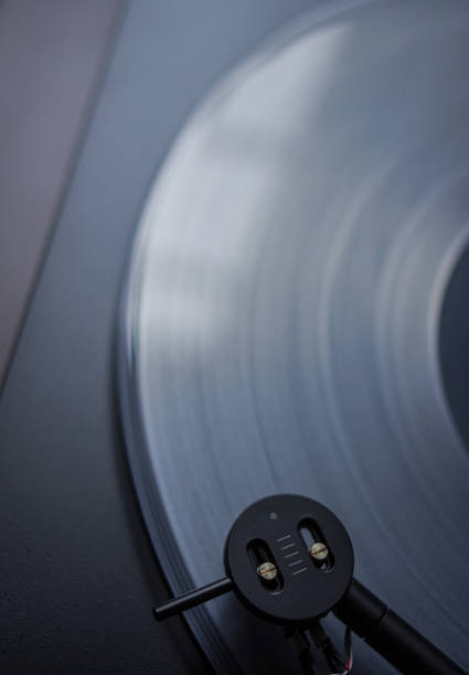 istock Modern round headshell with black cartridge on straight tonearm and transparent clear white vinyl record disc spinning on belt drive turntable 1170336593