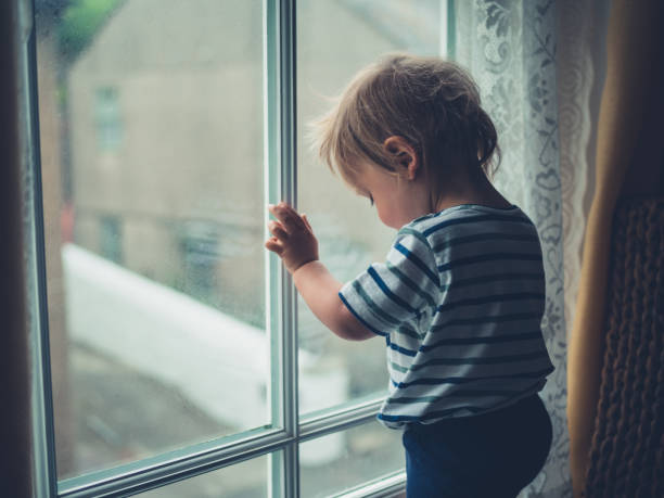 Little boy by window stock photo
