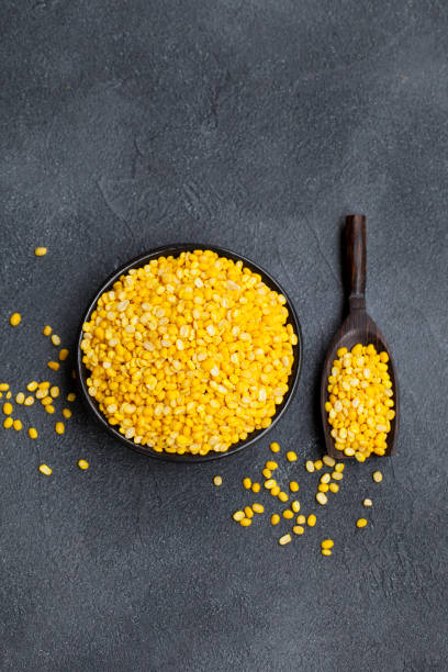 Yellow lentil in a black bowl on grey stone background. Top view. Copy space.
