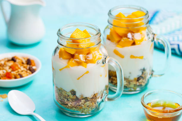 istock Fresh mango fruit with yogurt and granola in jars. Blue stone background. Close up. 1170343271