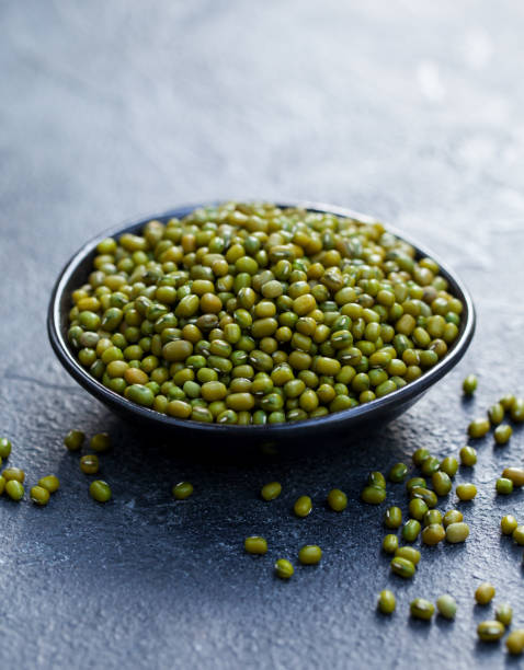 mung bean, green moong dal in wooden bowl. copy space. grey slate background. - green lentil imagens e fotografias de stock