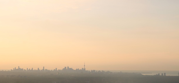 View from airplane of early morning sunrise over the city of Toronto Canada with CN Tower seen on the horizon on a hot hazy day