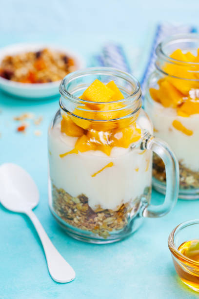 istock Fresh mango fruit with yogurt and granola in jars. Blue background. 1170344690