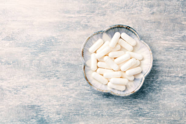 istock Glycine capsules. Concept for a healthy dietary supplementation. Nervous System Support. Bright wooden background. Directly Above. Copy space. 1170348054