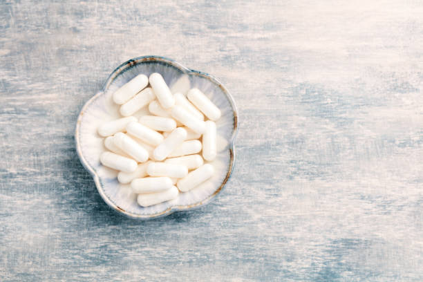 istock Glycine capsules. Concept for a healthy dietary supplementation. Nervous System Support. Bright wooden background. Directly Above. Copy space. 1170348146