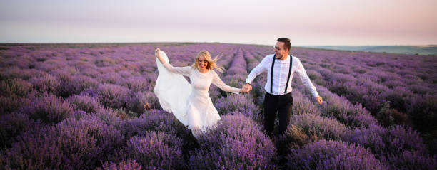 Happy newlyweds running along blooming lavender field
