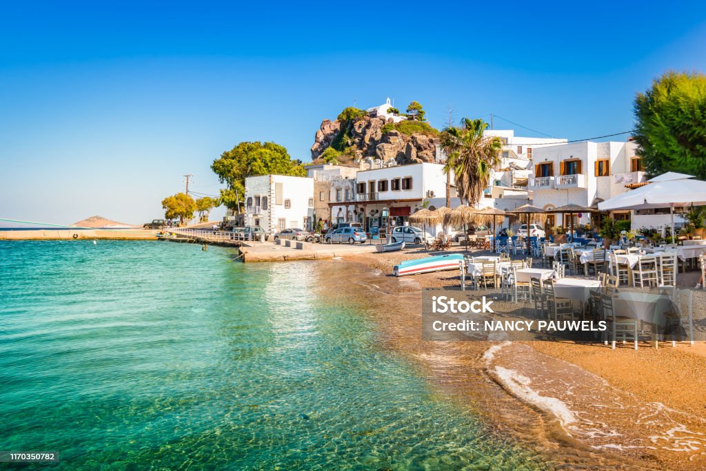 Patmos Island, Greece. Skala village and harbor view with beach at the port. Bright and colorful horizontal image of Skala town. Clear blue sky and small  beach close to the harbor of Patmos, Greece. Patmos Stock Photo