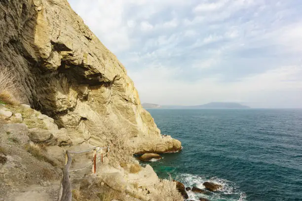 Photo of Calm Black sea at the foot of the Golitsyn trail in the Crimea - a popular tourist attraction of the village of Novy Svet on a cloudy day