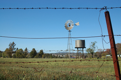 Windmill and tankstand in paddock, Queensland, Australia. Windmills are commonly used for pumping water from bores or dams to troughs for livestock.