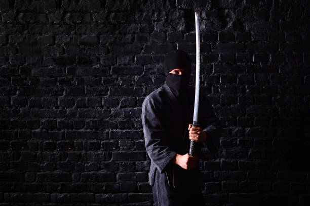 istock Ninja samurai with katana in attack pose on a dark brick wall background 1170361888