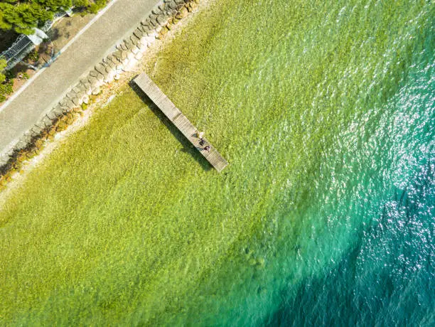 This is an aerial photograph of a wood dock going out into turquoise water