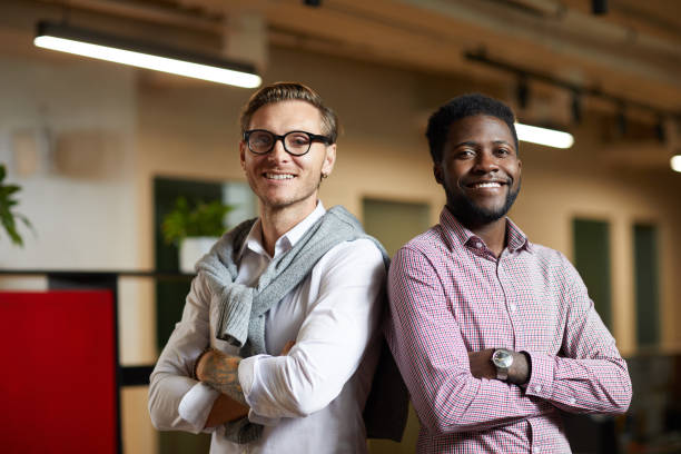 istock Positive confident young multi-ethnic startuppers standing back to back and looking at camera in office 1170370663