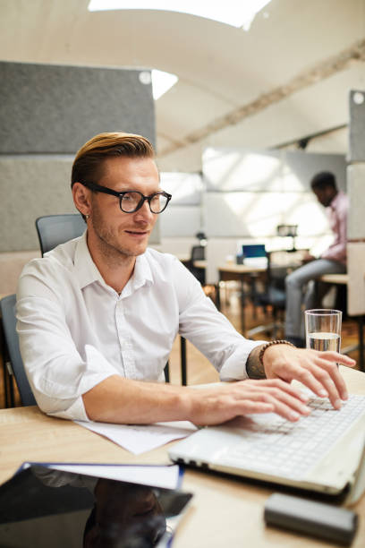 istock Content young man in eyeglasses sitting at desk and typing on laptop while working on article for social media 1170371139