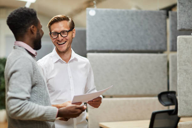 istock Optimistic young interracial colleagues standing in contemporary office and laughing while reading papers together 1170371799