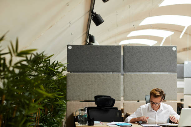 istock Busy young man in eyeglasses sitting at table in modern office with gradient partitions and using modern application for business 1170371831