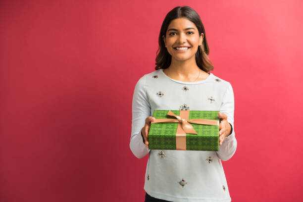 привлекательная улыбающаяся женщина, представляя подарочный ящик в студии - front view female isolated on red happiness стоковые фото и изображения