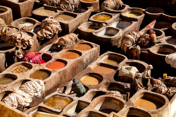 Fes, Morocco - March 31, 2023: Scene of the leather tannery, with workers and stone vats filled with various colors. Fes, Morocco
