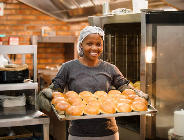 Shot of female chef with baked tray burger buns at restaurant kitchen