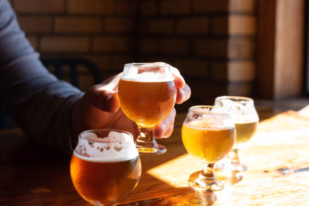 Man raising a glass of beer, tasting samples from a craft beer flight at local brewery stock photo