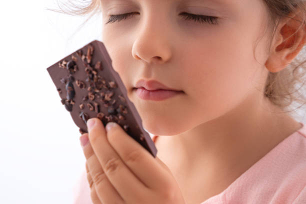 красивая маленькая девочка вкус шоколада, как профессионал - нарушение какао-бар, пахнущие, есть - dark little girls child happiness стоковые фото и изображения