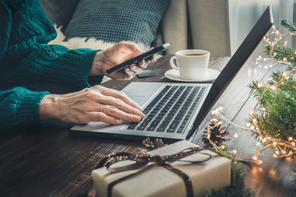 Christmas sales. Woman shopping with smartphone by laptop in home interior. Xmas. Planning holidays. Christmas sales. Woman shopping with smartphone by laptop in home interior. Xmas concept. Planning holidays. holiday shopping stock pictures, royalty-free photos & images