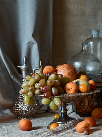 A classic still-life in the Dutch old masters painting style with  fruits on a silver, platter, silver carafe and glass botles