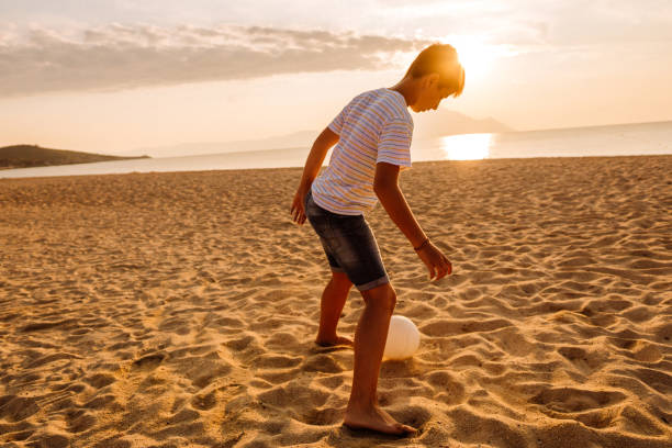 istock Boy playing soccer on the beach 1170385152