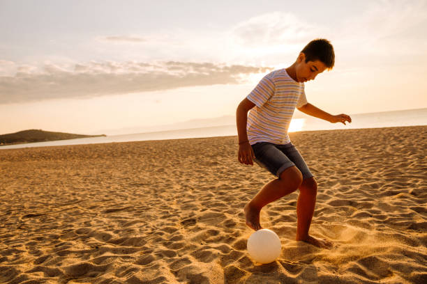 istock Boy playing soccer on the beach 1170385165