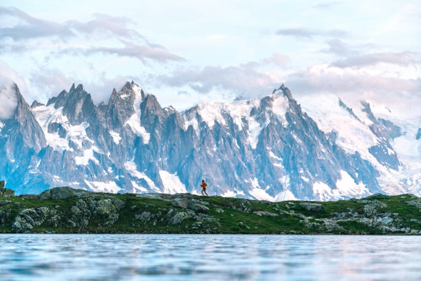 una joven corre a lo largo del lago bajo las montañas - solitude mountain range ridge mountain peak fotografías e imágenes de stock