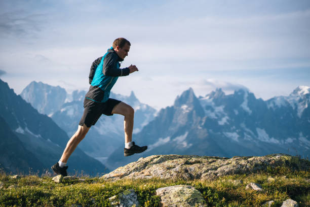 Trail runner bounds along mountain meadow in the morning