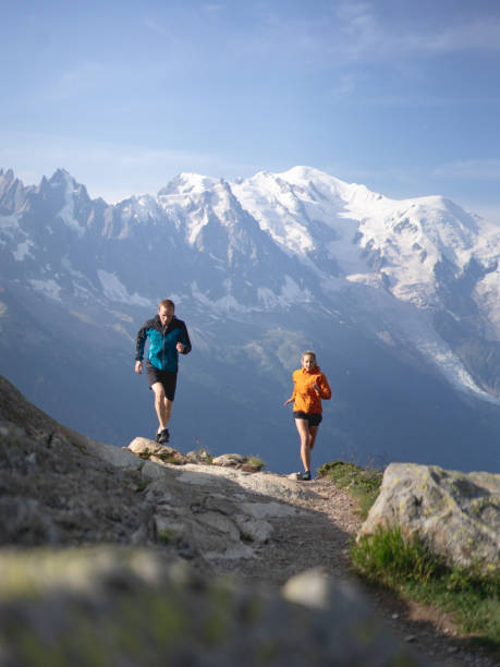 le sentier de couples courent par des montagnes dans la lumière de matin - cross coat photos et images de collection