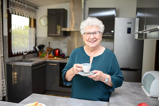 happy senior active woman drinking coffee in a modern kitchen at home