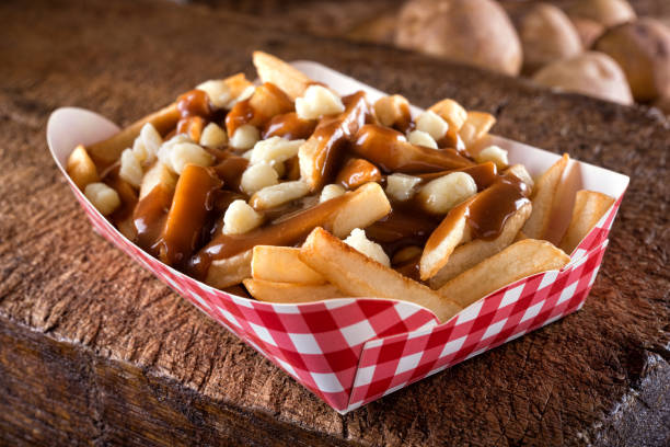 Putin A serving of delicious poutine with french fries, cheese curds and gravy on a rustic wooden board. poutine stock pictures, royalty-free photos & images