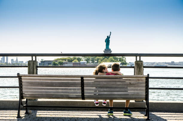 Two kids looking at Statue of Liberty from the Liberty State Park in Jersey city during summer day