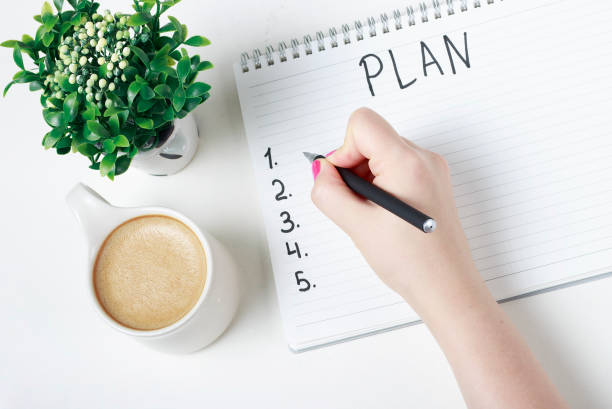 istock Female hand writes a plan in a notebook, goal setting concept 1170426282