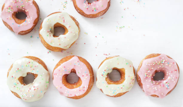 istock Homemade donuts decorated with colored icing and colored sugar on a light background. 1170431845
